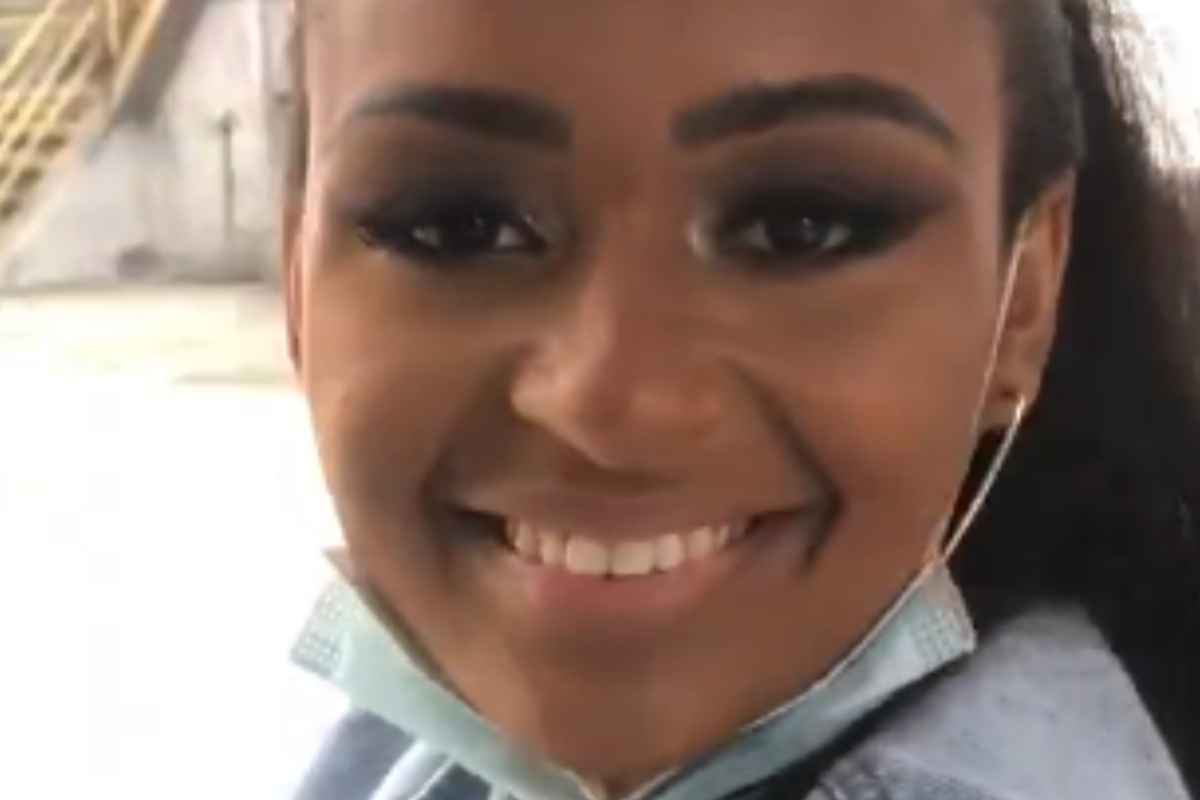 Natália Deodato sorridente no ônibus com máscara no queixo