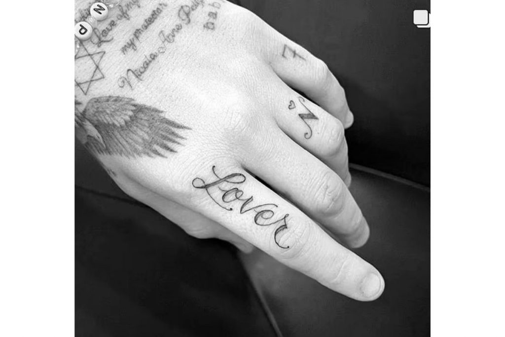 Tatuagem de Brooklin Beckham com  palavra "Lover" no dedo indicador 