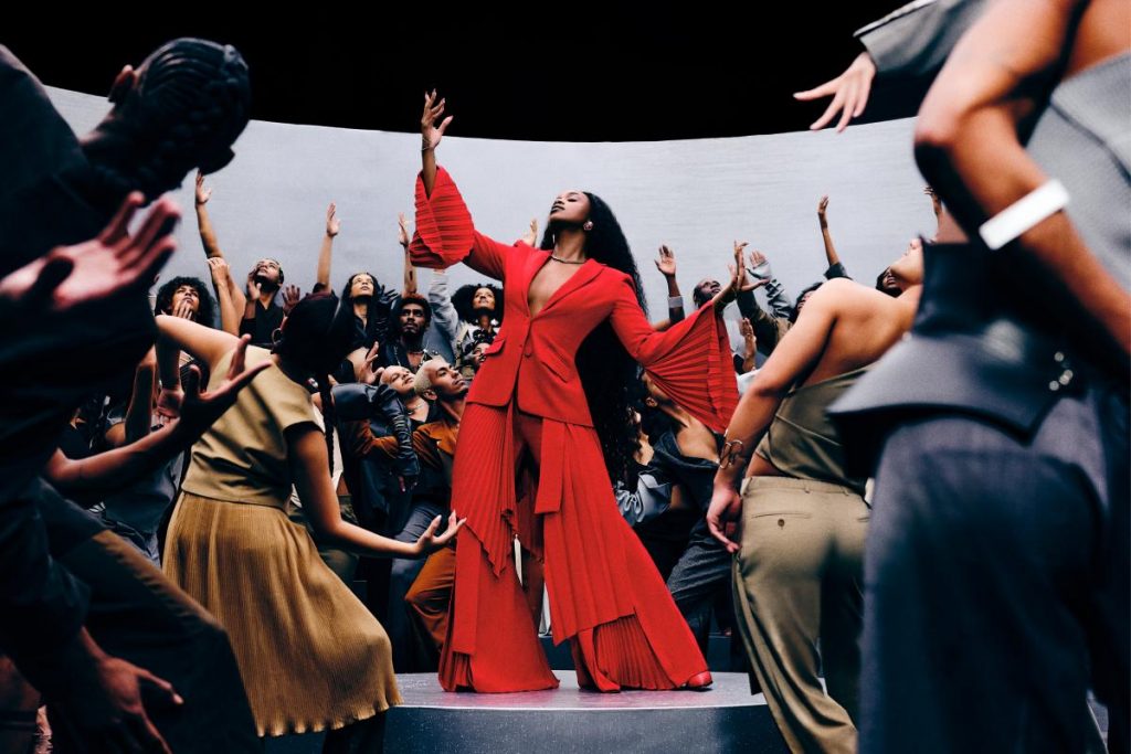 iza estilosa com look vermelho rodeada de dançarinos no clipe de fé