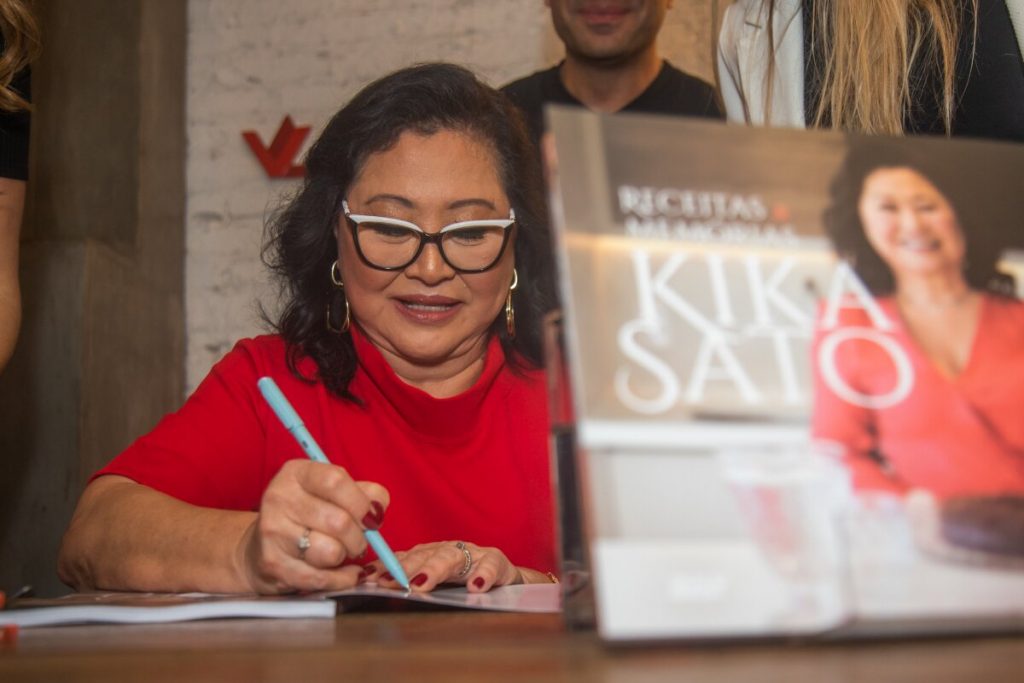 Kika Sato, de vermelho, autografando livro