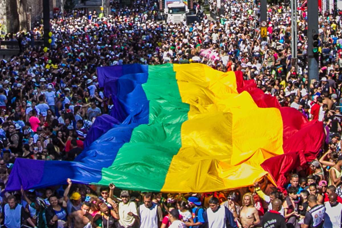 público desfilando e carregando bandeira do arco-íris em parada do orgulho LGBTQIAP+ de São Paulo