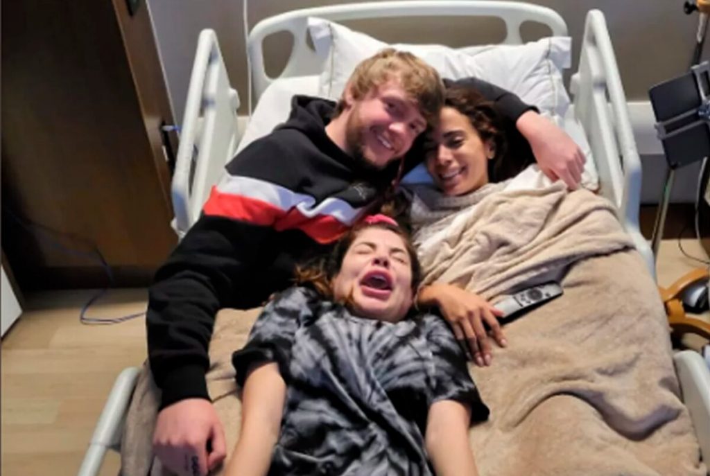 Murda Beatz abralado a Anitta na cama do hospital e GKay entre eles, imitando um neném - Foto: Reprodução/ Twitter @Gkay