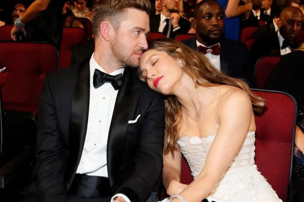 Justin Timberlake de terno preto, beijando a cabeça de Jessica Biel, de vestido branco 