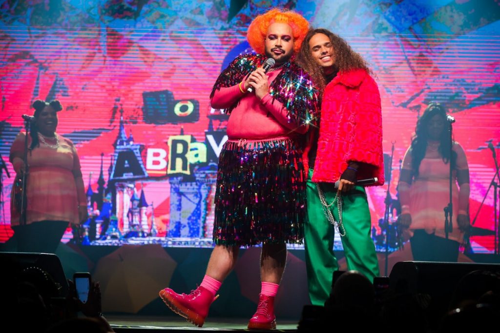 Tiago Abravanel fantasiado e Vitão de calça verde e casaco vermelho, no palco do Baile do Abrava