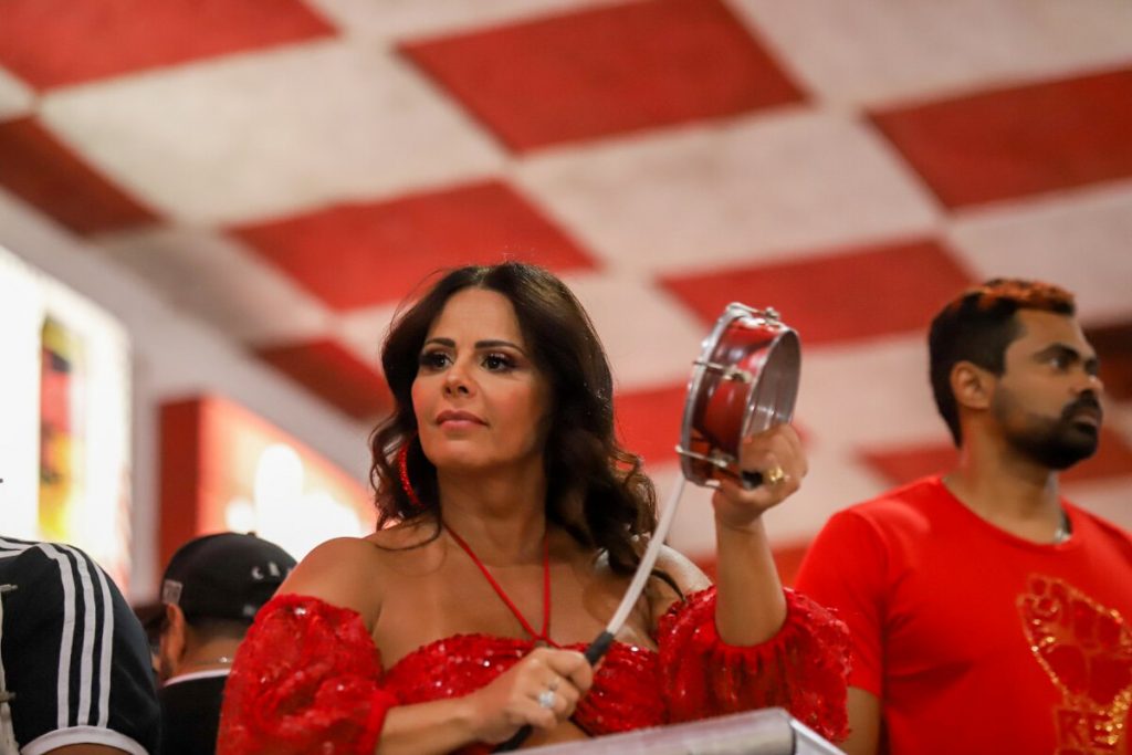 Viviane Araújo, de vermelho, tocando tamborim 