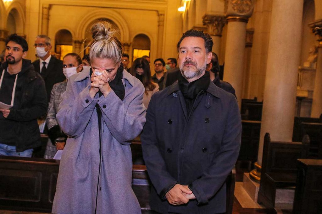 Adriane Galisteu reza, ao lado do marido, Alexandre Iódice, em missa de sétimo dia de Jô Soares