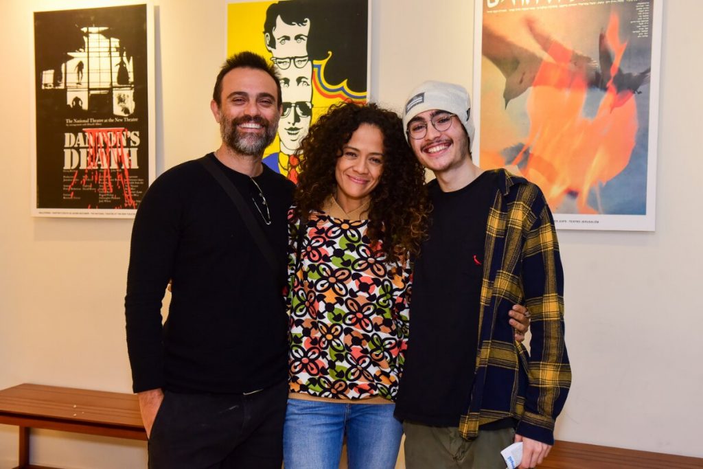 Aline Borges, de calça jeans e blusa estampada, abraçada ao marido, Alex Nader, de preto, e ao filho dele, de boné pra trás, camisa preta e casaco estampado