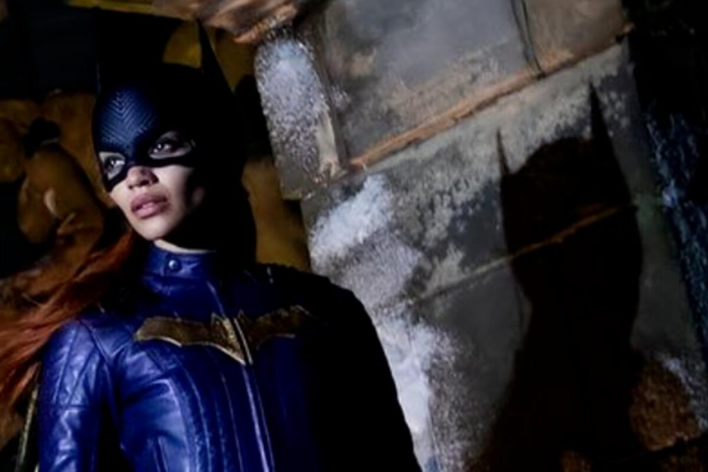 Batgirl, caracterizada com o de uniforme azul, e máscara, olhando para o lado