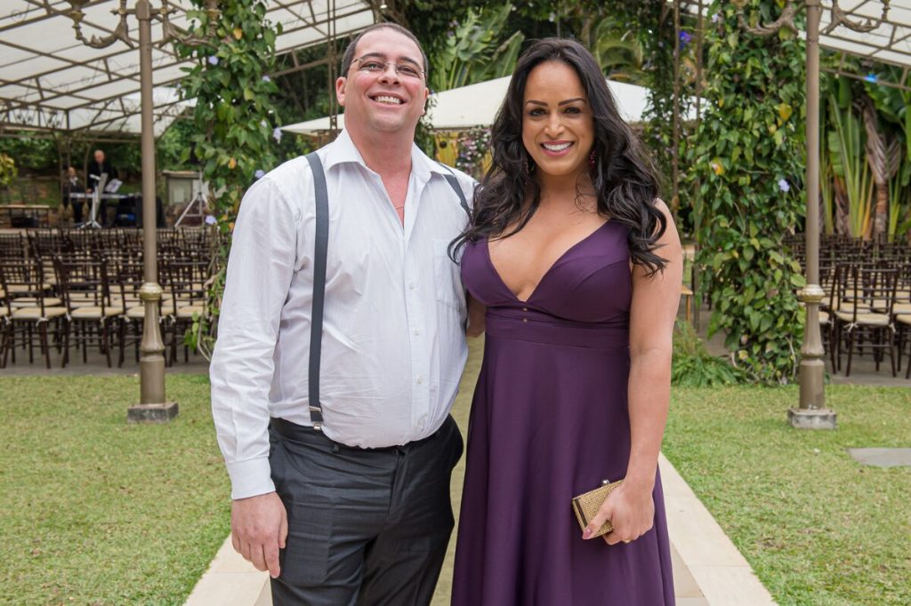 Paulo Roberto de camisa branca e calça cinza, e Lisa Gomes de vestido roxoe Lisa Gomes, padrinh