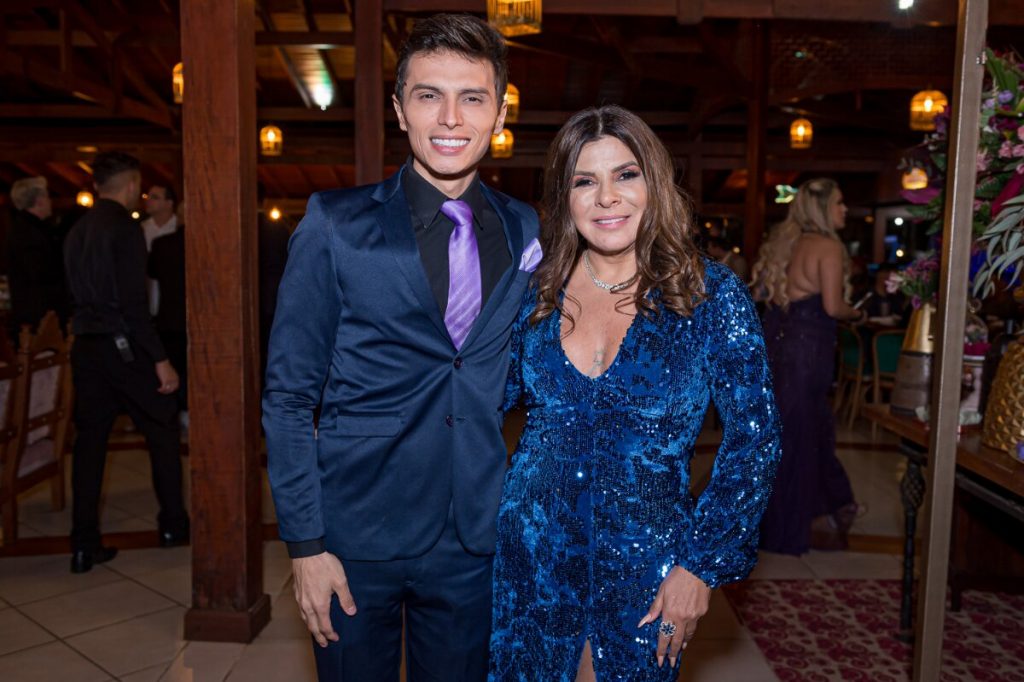 Gabriel Torres de blazer e terno azul escuro, com Mara Maravilha, de vestido brilhante azul escuro