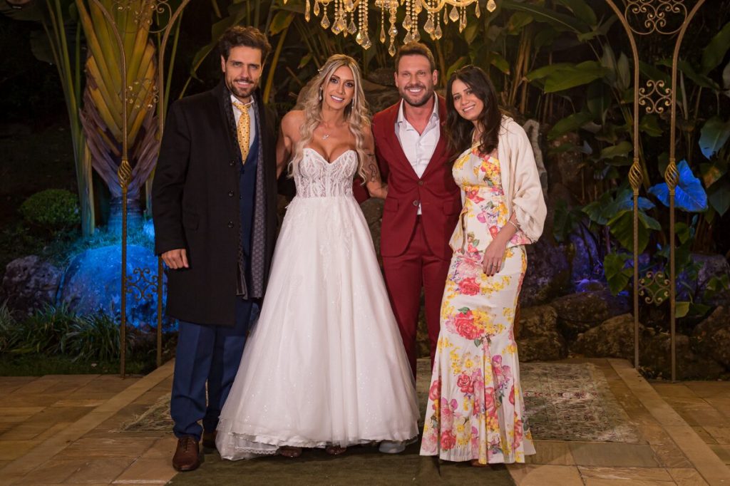 Tiago Aracan de sobretudo, co a julher, de vestido banco estampado de flores,  preto, ao lado dos noivos