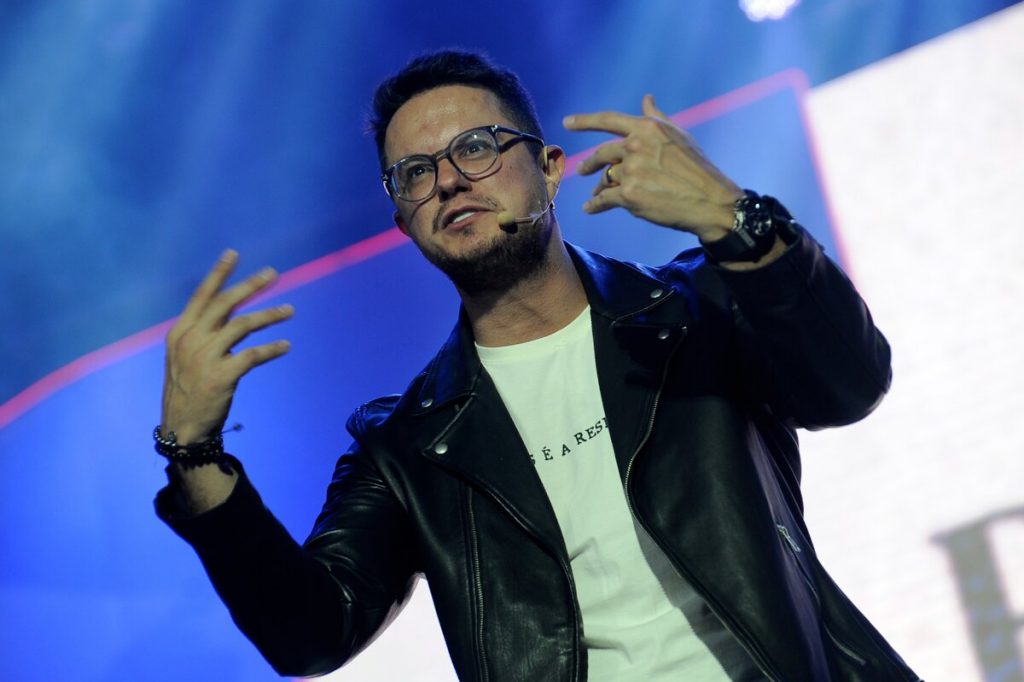 Deive Leonardo de jaqueta preta e camisa branca, de óculos de grau