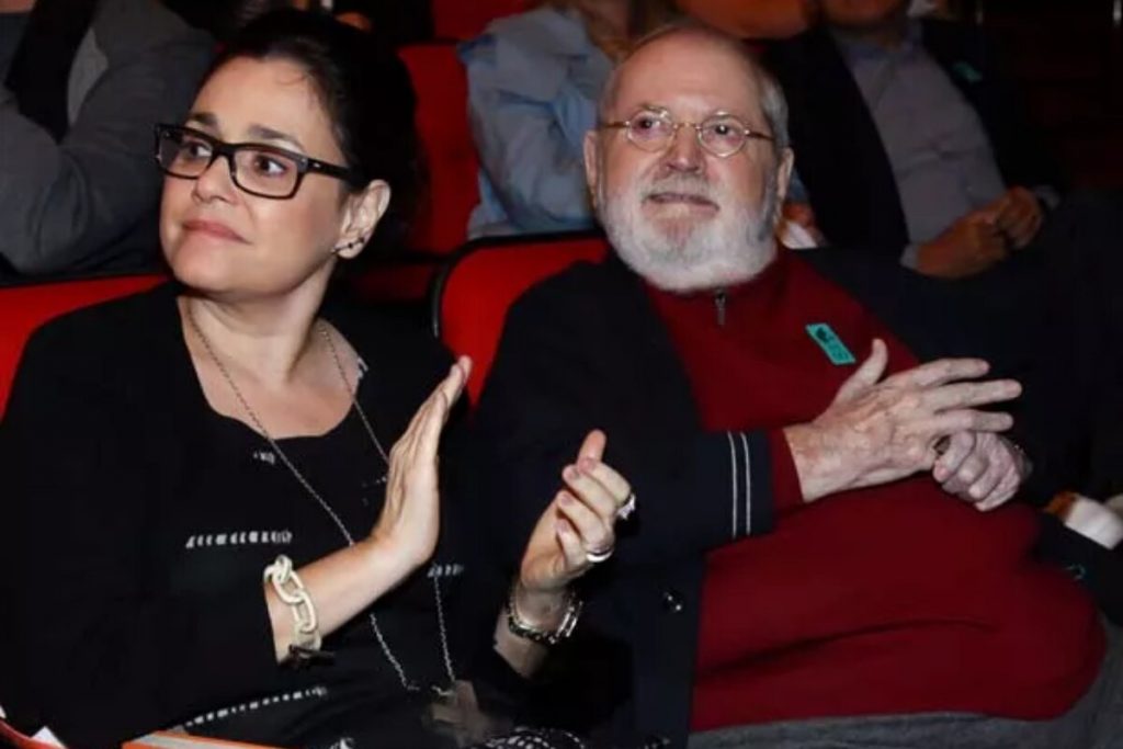 Flavia Pedras Soares e o ex-marido, Jô Soares, sentados numa plateia de teatro, aplaudindo