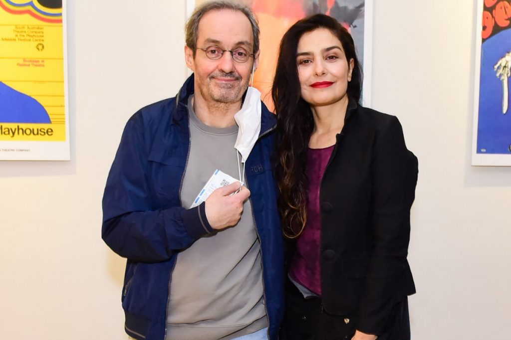 Daniel Dantas de casaco azul, camisa cinza, máscara de proteção na orelha, abraçado a Letícia Sabatella, de blazer preto e camisa roxa