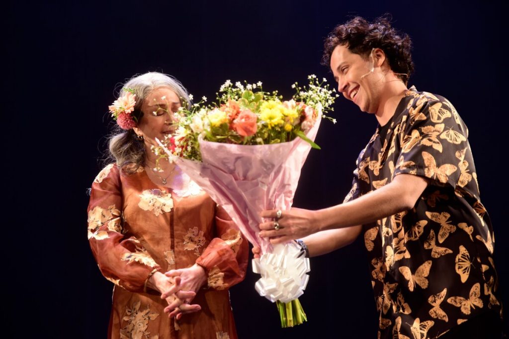 Nívea Maria recebendo flores de Arlindo Lopes, no palco