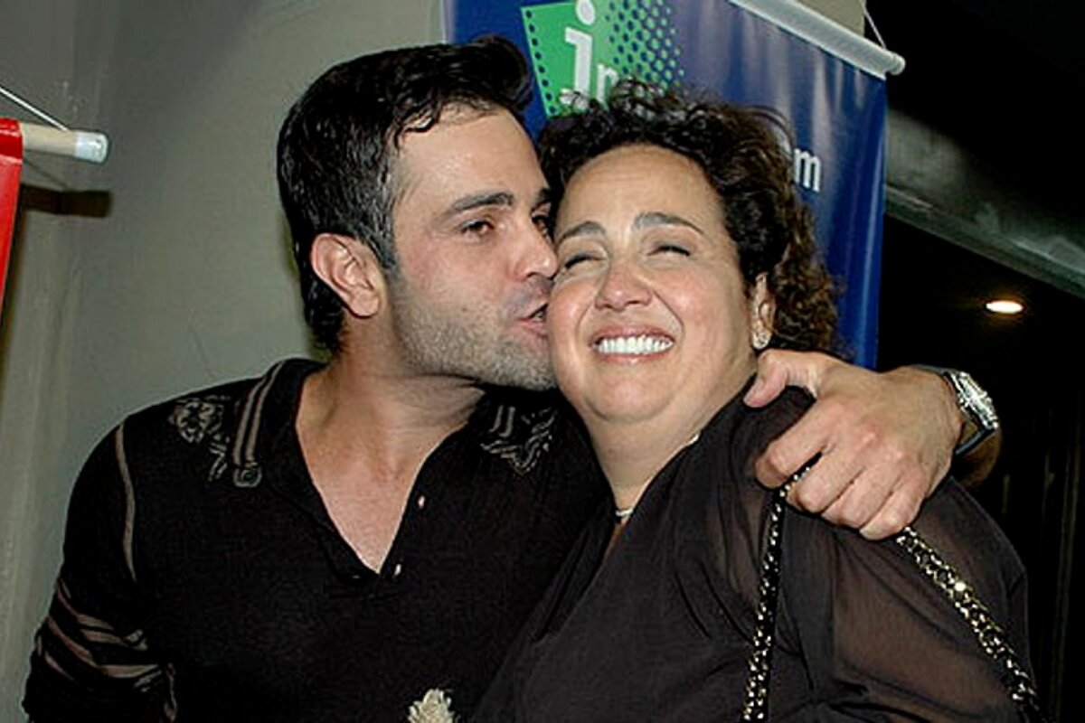 Rodrigo Phavanello dando beijo no rosto de Claudia Jimenez, que sorri. ambos de preto