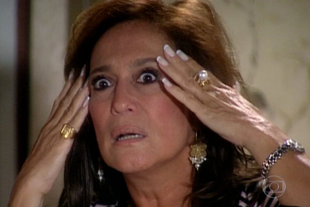 Susana Viera como Maria do Carmo, de Por amor, com expressão de espanto, com as mãos na cabela