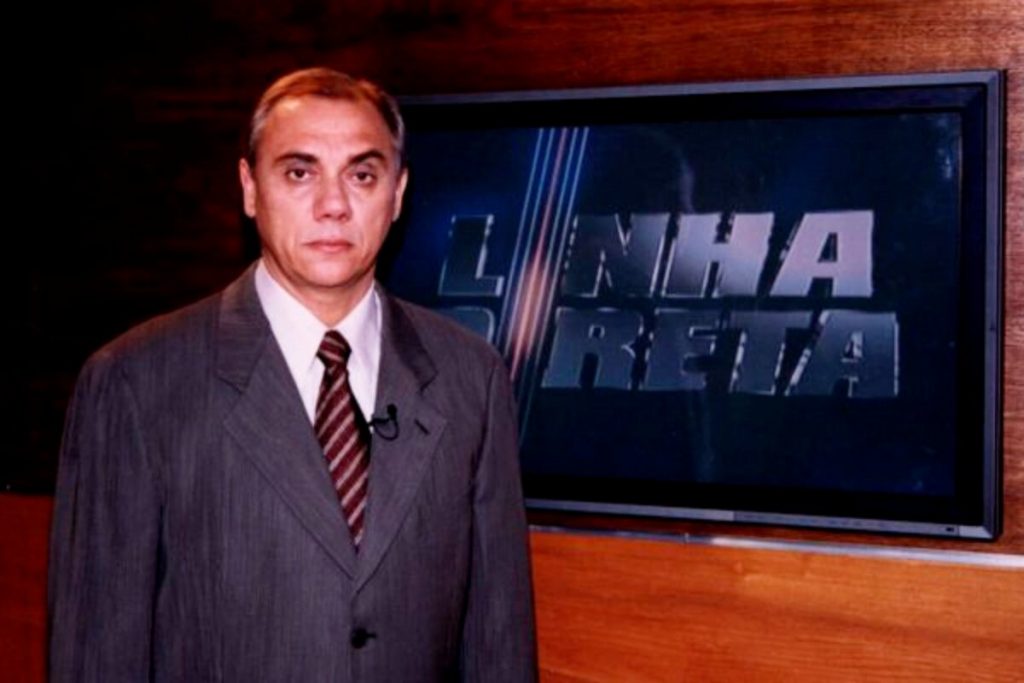 Marcelo Rezende, de terno e gravata, posado na logo do programa 'Linha Direta'