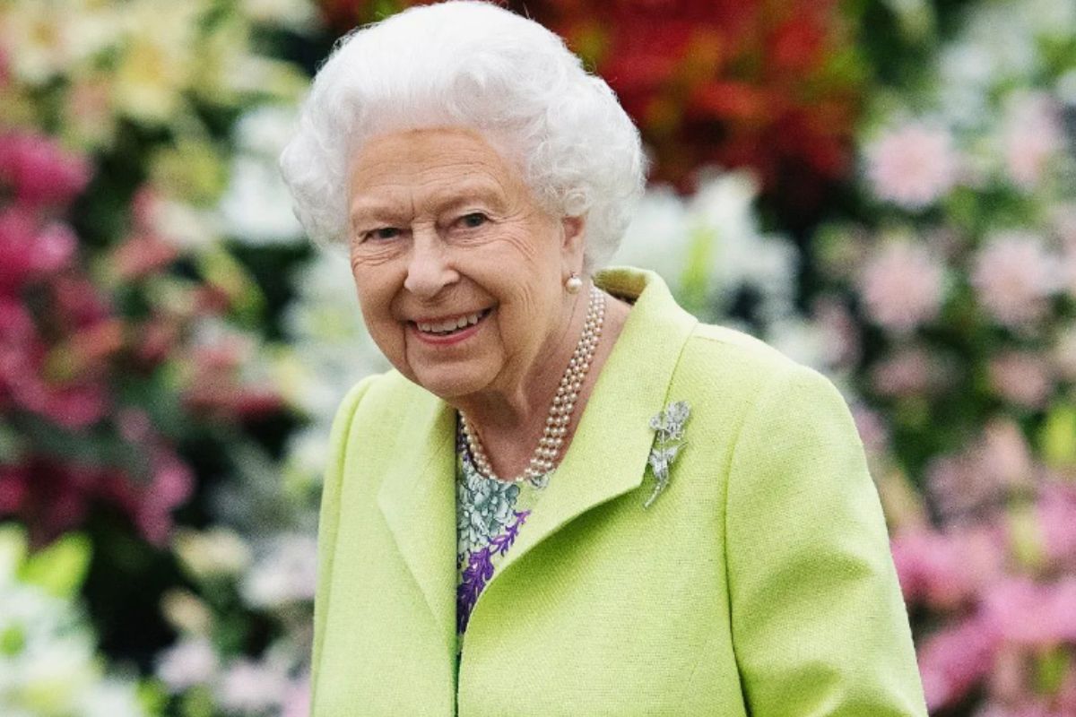 Rainha Elizabeth II com roupa verde claro, sorridente em jardim
