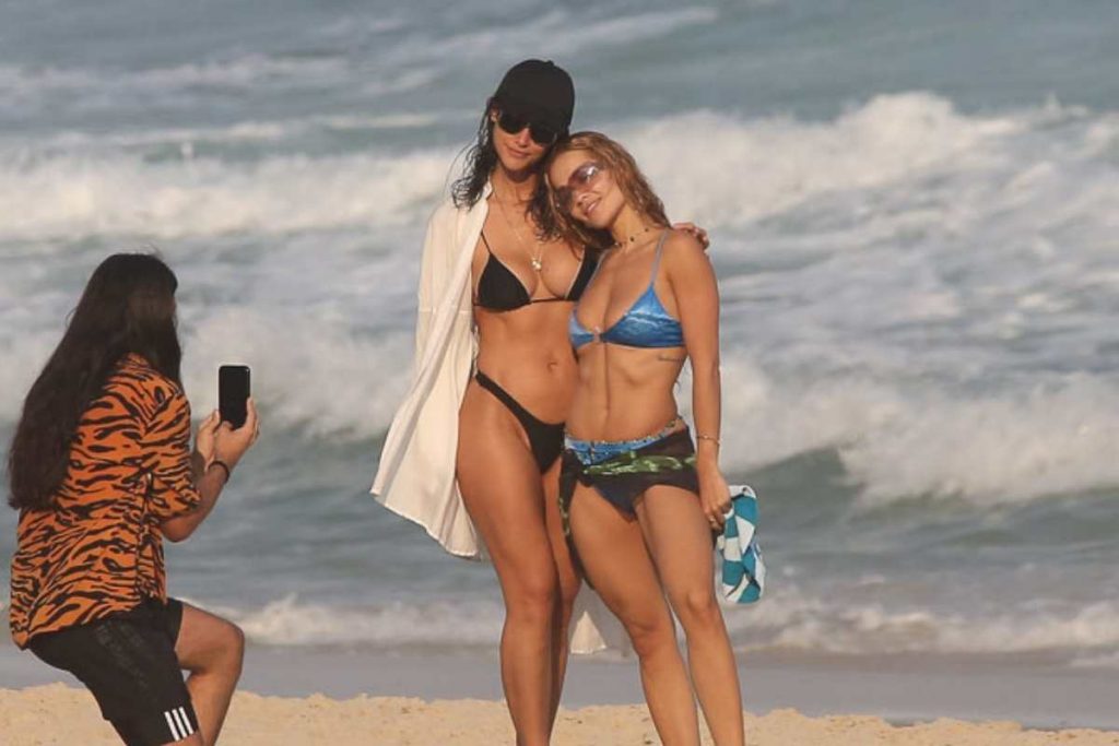 Rita Ora e Débora Nascimento posando para foto em praia do Rio de Janeiro