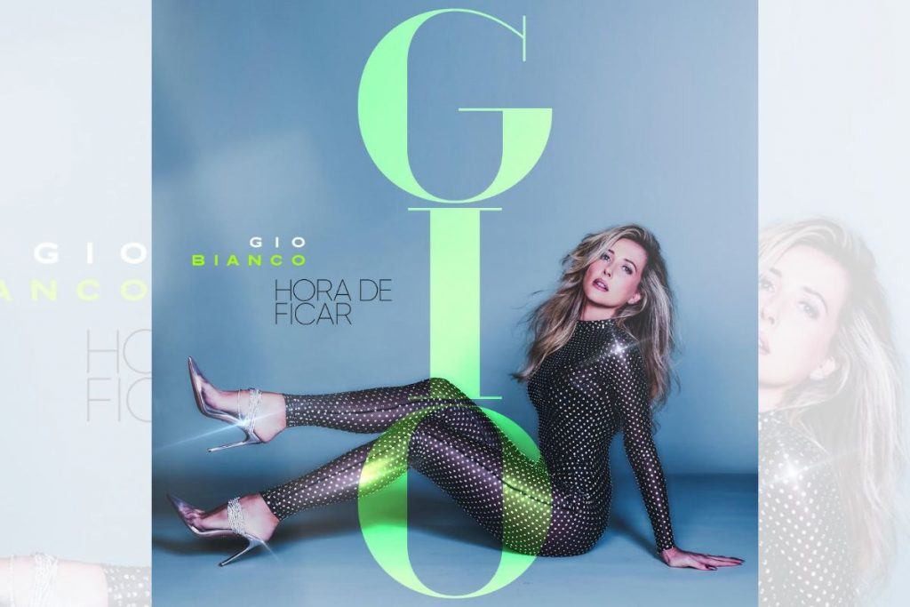 Capa do novo single de Gio Bianco, onde ela aparece sentada com macacão preto cheio de apliques brilhantes