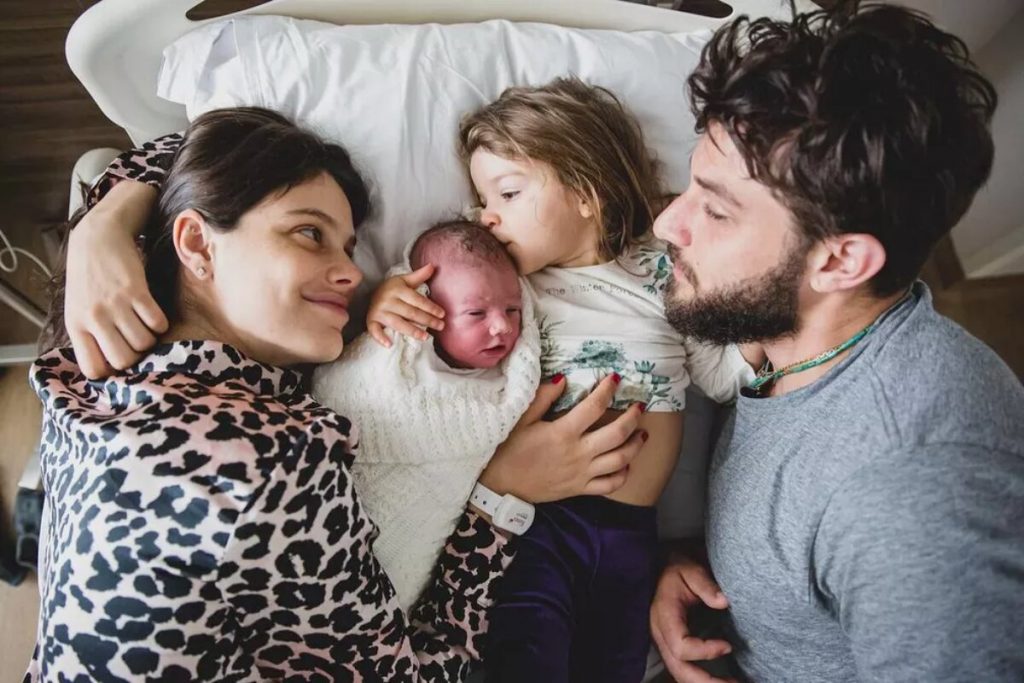 Laura Neiva, os filhos José e maria, e hay Sueede, deitados na cama José, segundo filho de Laura Neiva e Chay Suede