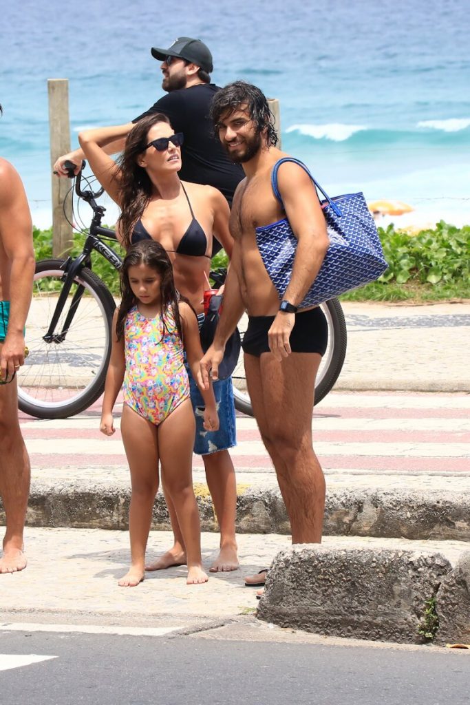 Deborah Seco Hugo Mora de sunga preta e Maria Flor de maiô, saindo da praia 