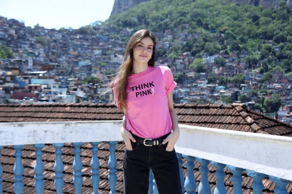 Camila Queiroz de camisa outubro rosa, calça preta com as mãos no bolso