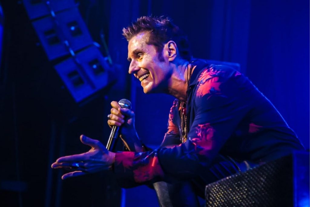 Dinho Ouro Preto sorri cantando