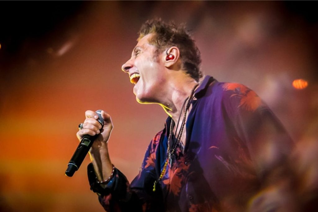 Dinho Ouro Preto cantando no microfone, palco Espaço Unimed