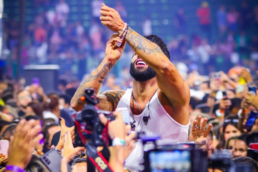 Gusttavo Lima se jogando nos fãs em show no festival Buteco