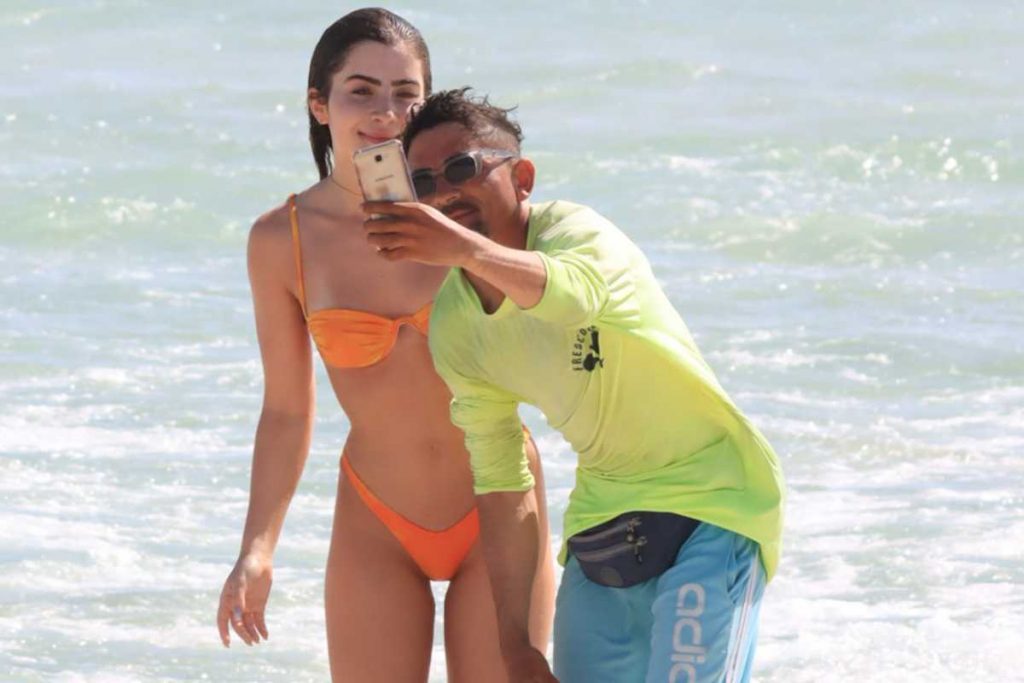 Jade Picon tirando foto com fã na praia da Barra da Tijuca