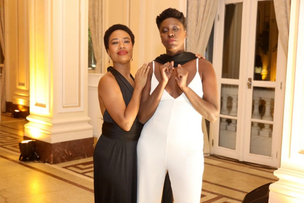 Mariana Nunes de vestido preto e Tati Vilela de macacão branco