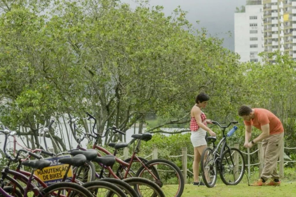 Leonor (Vanessa Giácomo) recebendo ajuda de Caíque (Thiago Fragoso) com a bicicleta, em "Travessia"