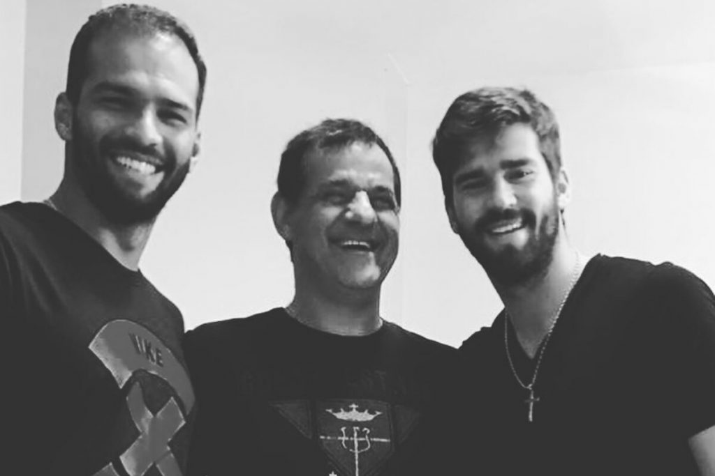 Muriel, João e Alisson Becker, todos de preto, sorrindo, foto em preto e branco