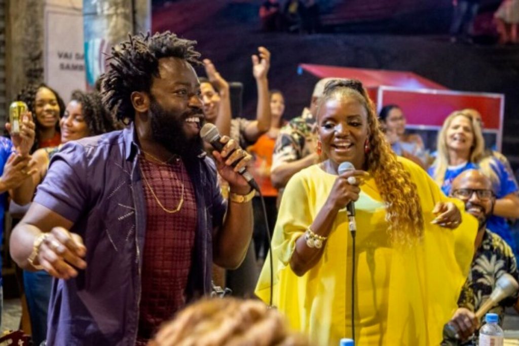 Oberdan (Douglas Silva) e  Jussara (Mary Sheila), de vestido amarelo, em "Todas as Flores", cantando pagode