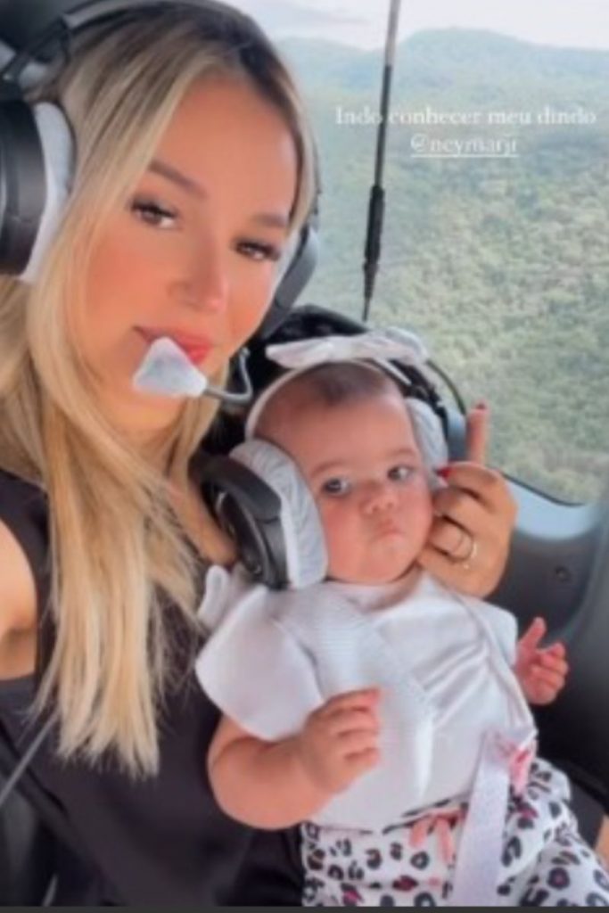 Bianca Coimbra com a filha no colo, em um helicóptero