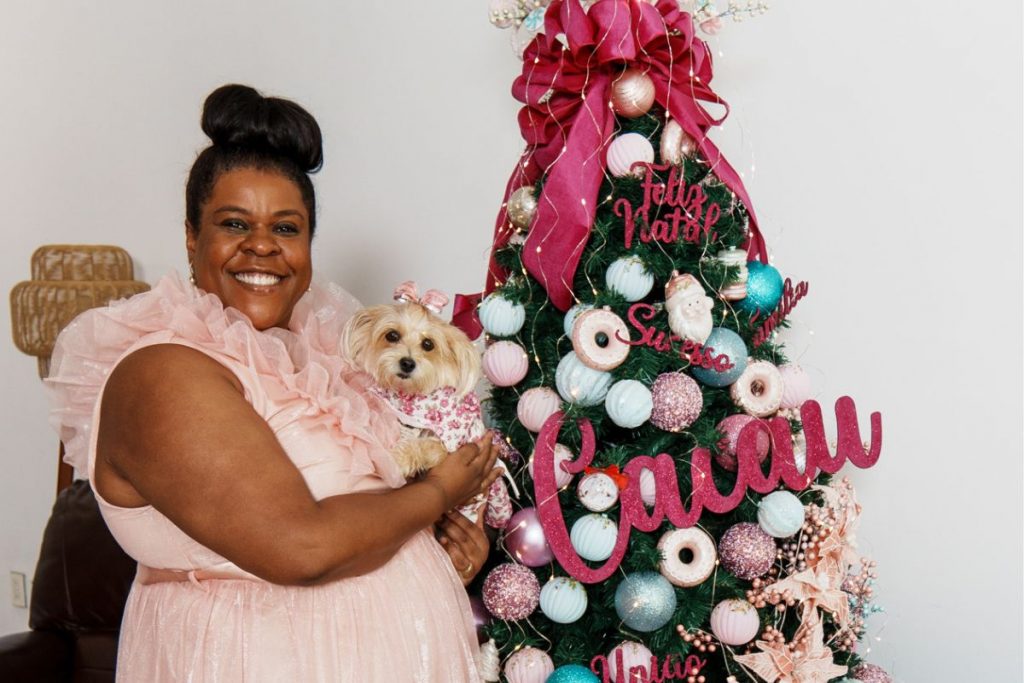 Cacau com a cachorrinha, Sambinha no colo, em frente a árvore de Natal
