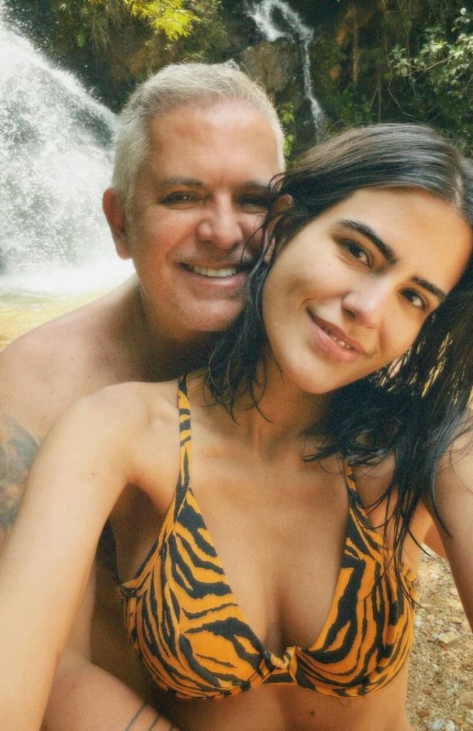 Orlando Morais sem camisa, abraçado à filha, Antonia, de biquini, na cachoeira