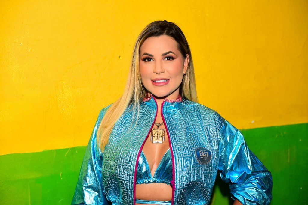 Deolane de conjunto azul, barriga de fora, sorrindo