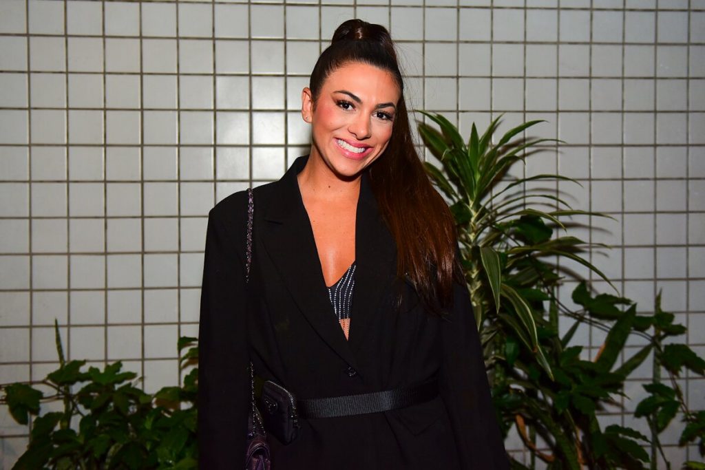 Pétala de roupa preta, cabelo preso, sorrindo