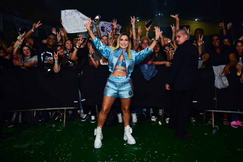 Deolane diante dos fãs, de braços abertos