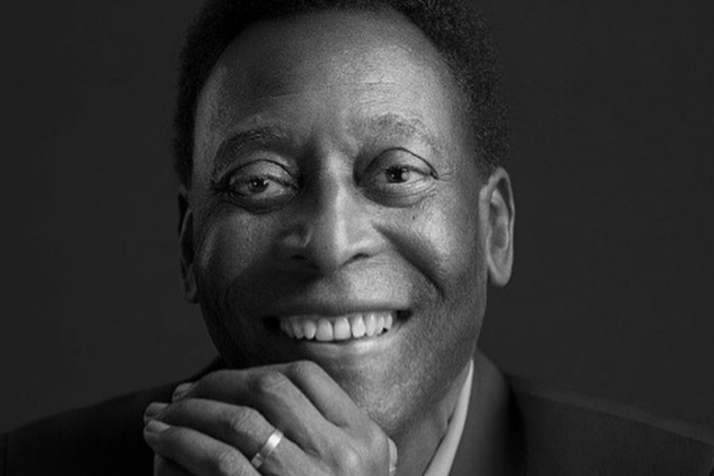 pelé sorrindo de terno em foto preta e branca