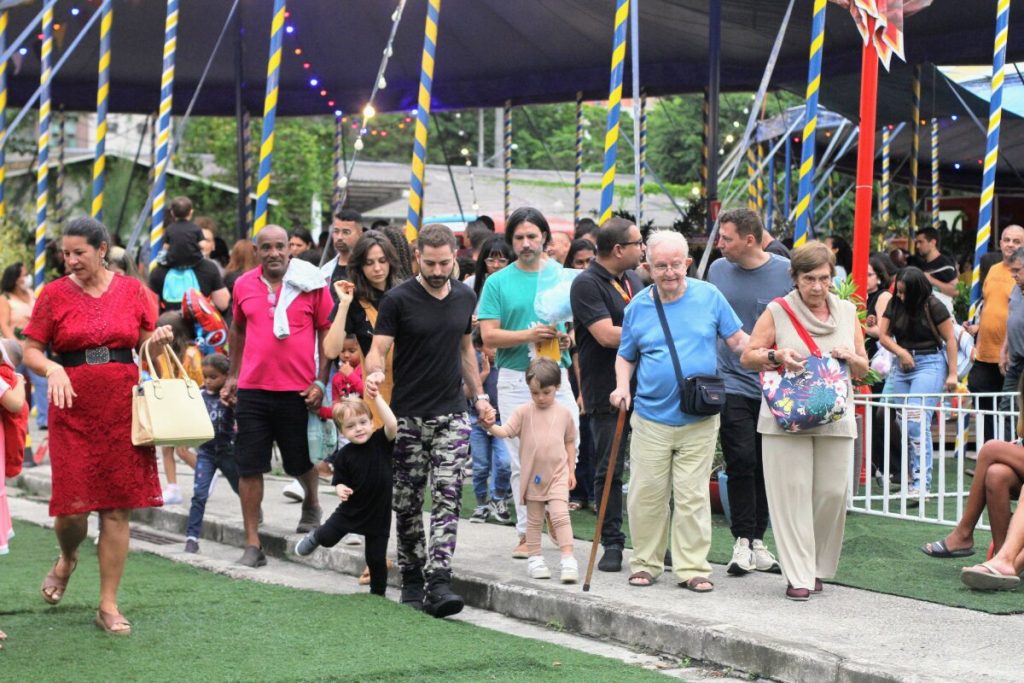 camisa preta, calça camuflada, de mãos dadas com os filhos, chegando ao circo