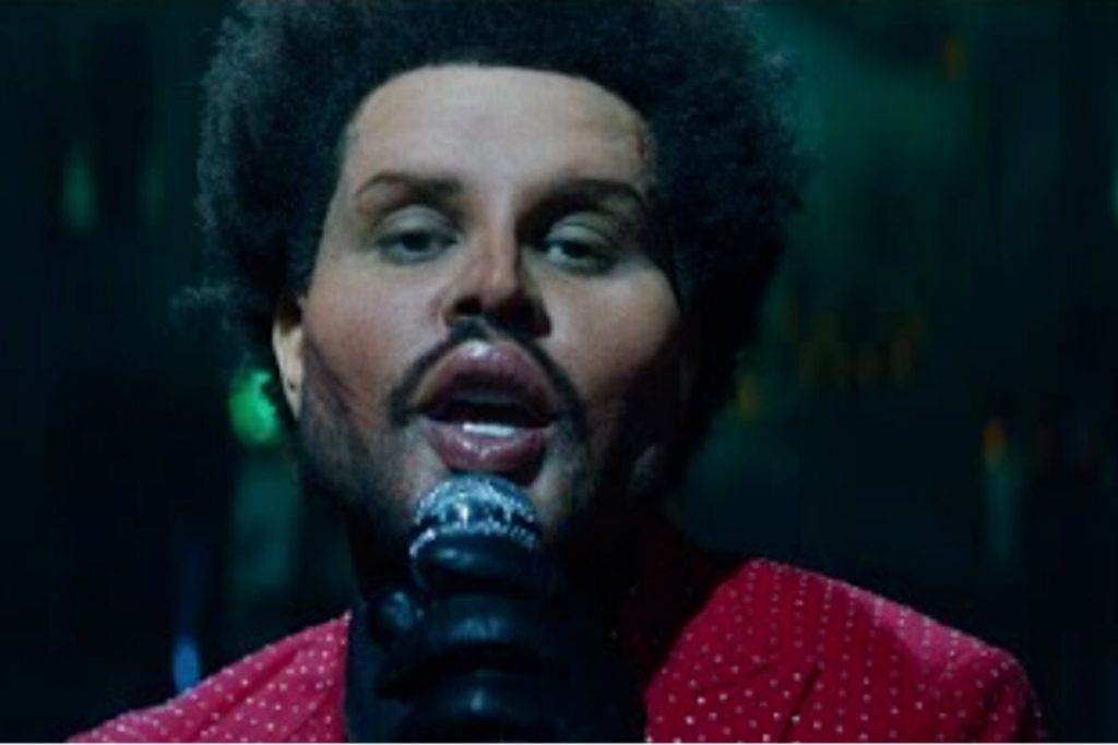 The Weeknd cantando, de blazer vermelho