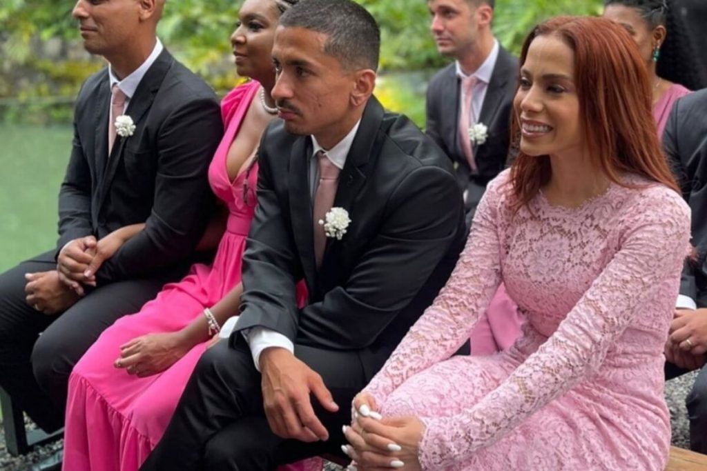 Renan e Anitta sentados assistindo a cerimônia de casamento do irmão 