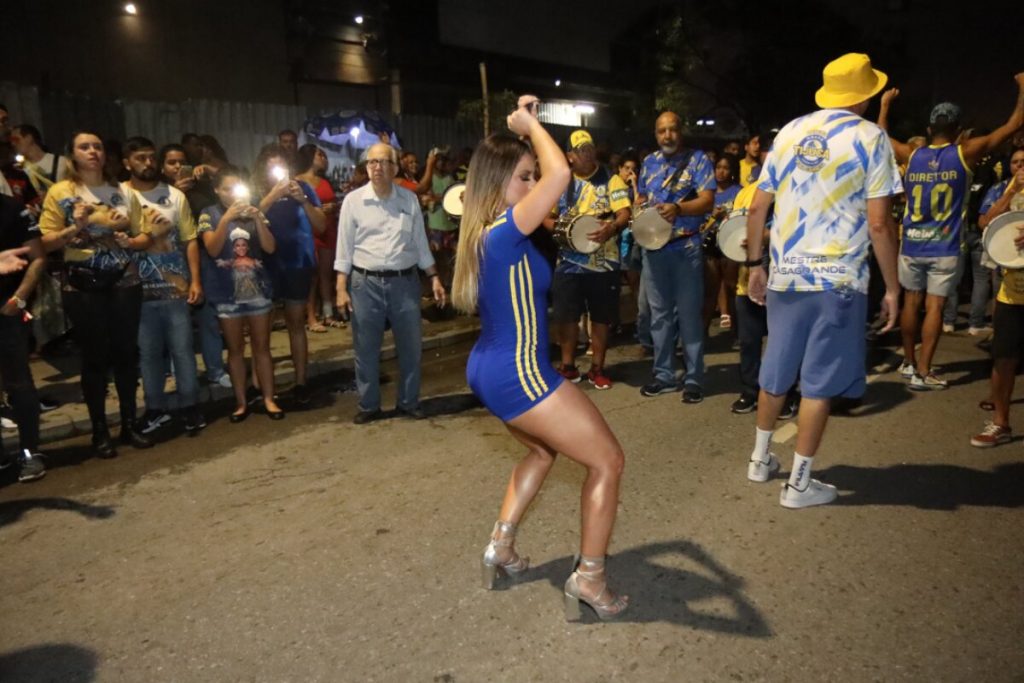 Lexa de macaquinho azul com listras laterais amarela e fecho eclair frontal