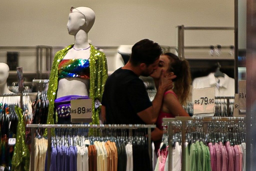 Rafael Cardoso de camisa preta e a namorada, Vivian Linhares, beijando no shopping