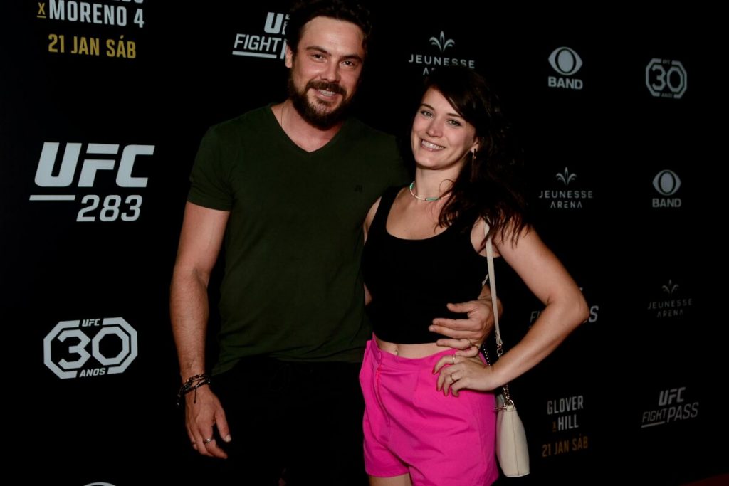 Sergio Guizé todo de preto, abraçado a Bianca Bin, de cropped preto e calça rosa