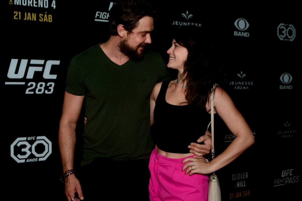 Sergio Guizé todo de preto, abraçado a Bianca Bin, de cropped preto e calça rosa